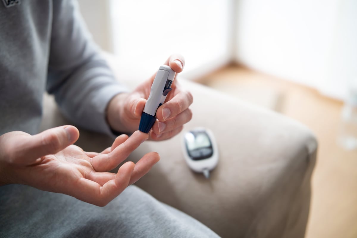 Close-up of a man's hand checking blood sugar level with glucometer